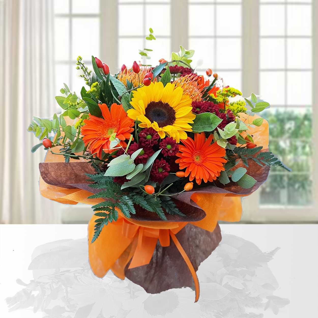 Bouquet Colori d'Autunno con girasoli gialli, gerbere arancioni, crisantemi bordeaux, bacche rosse e foglie di eucalipto. Confezione regalo marrone e arancione, su sfondo finestra.