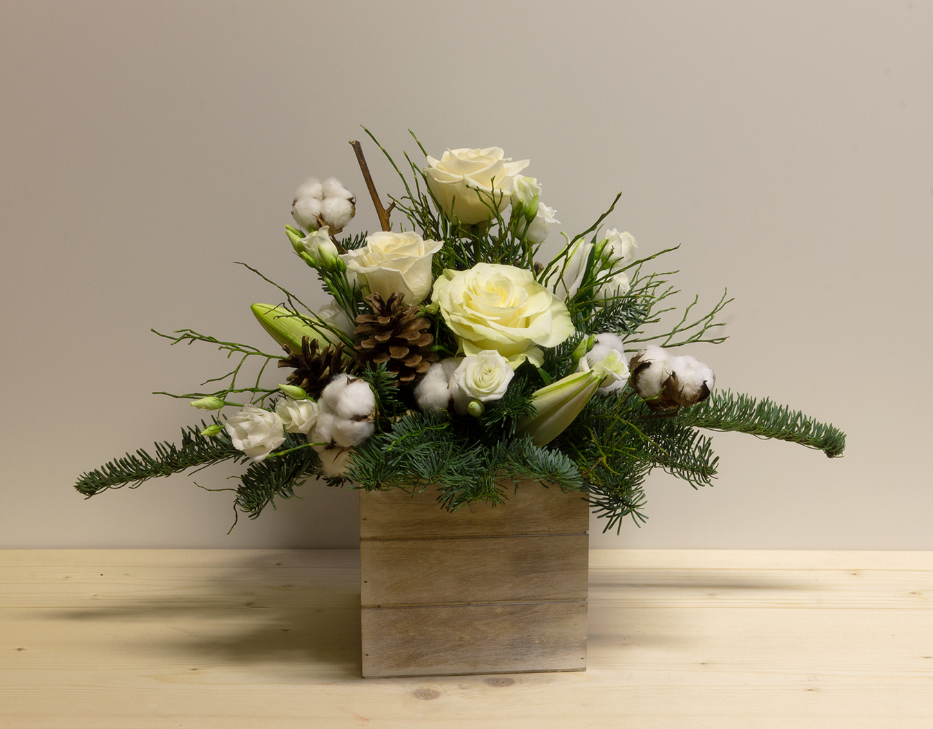 Armonia Natalizia: centrotavola in cassetta di legno con rose bianche, cotone naturale, pigne e rami di abete.