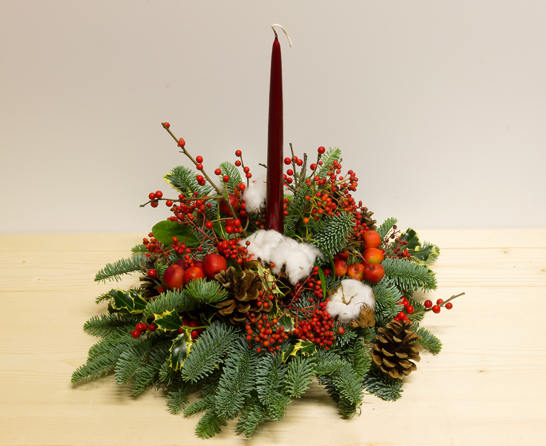 Centrotavola Buone Feste natalizio con candela rossa, rami di abete, pigne, bacche e cotone