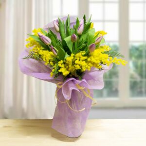 Bouquet Woman con 10 tulipani lilla e rami di mimosa gialla confezionato in carta velina viola con nastro giallo.