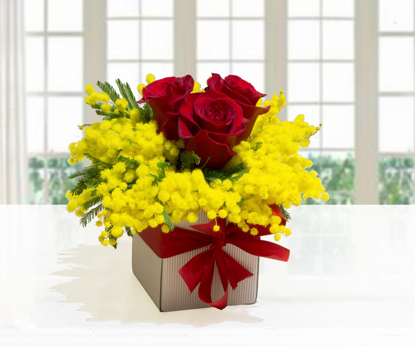 Composizione Red Rose Woman con 3 rose rosse e mimosa gialla in scatola quadrata rigata con fiocco rosso.